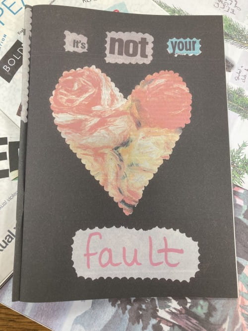 Page of zine which has a heart in the centre and reads "it's not your fault"