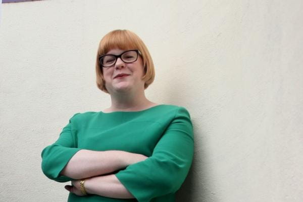 Emma Ritch folds arms and looks to camera smiling